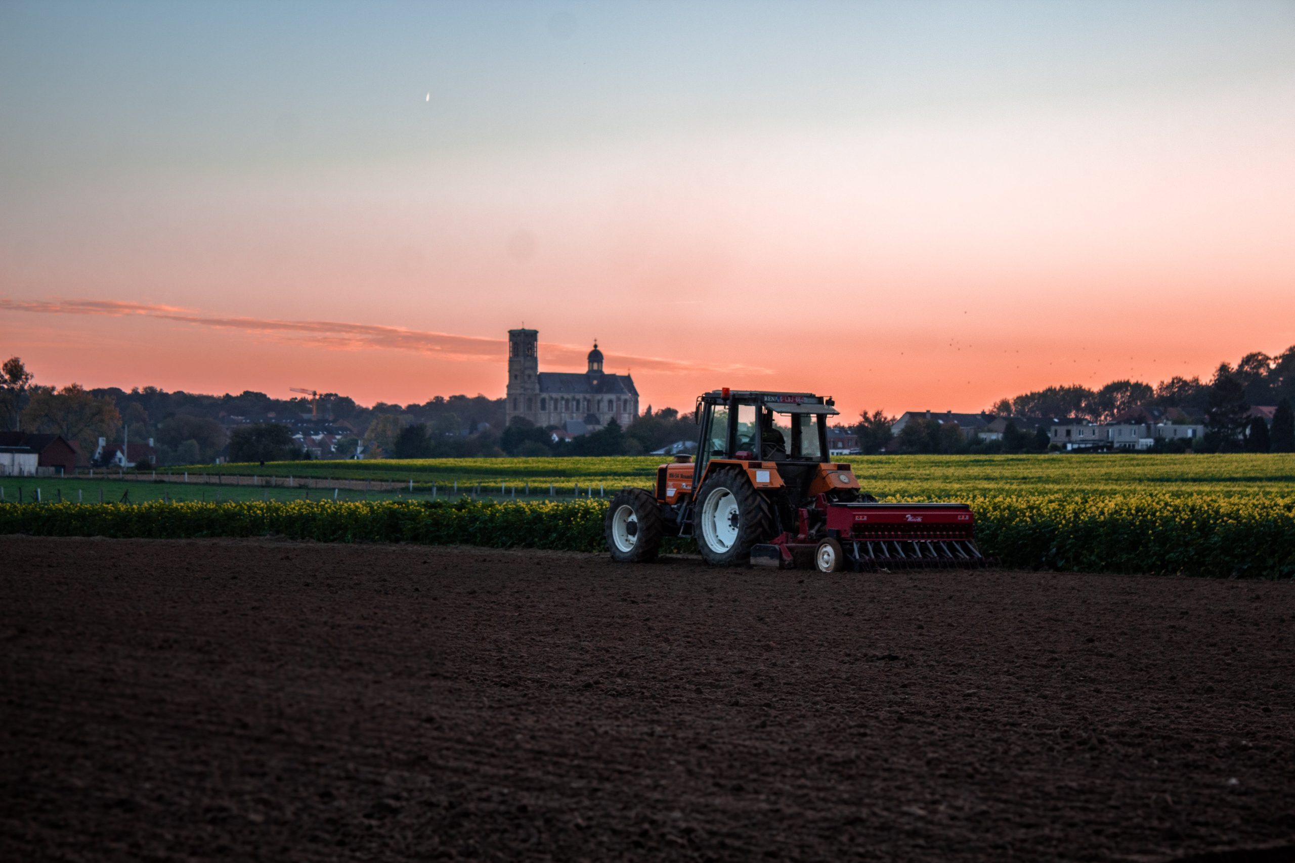 Una imagen de un agricultor preparando el campo para la siembra. El agricultor está usando un tractor para arar el suelo